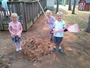 Children holding rakes and brooms