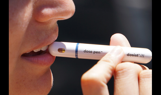 A teenager holds a vape pen to their mouth.