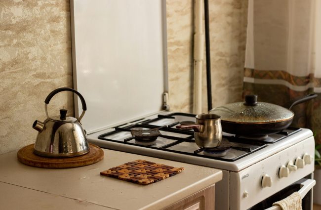 A small stove with a pan and a tea kettle.