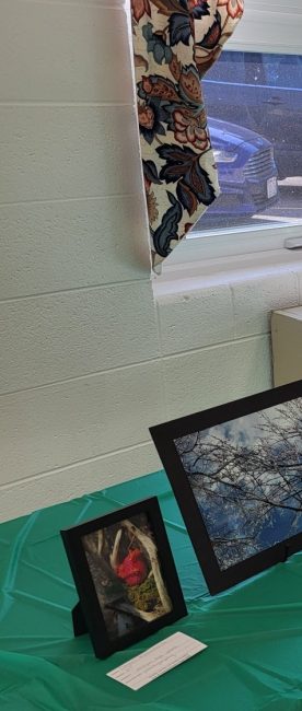 Art is displayed on a long table with a green tablecloth.