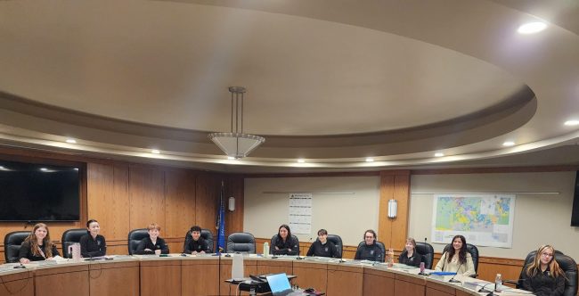 A large circle conference table with youth panelists sitting at the chairs.